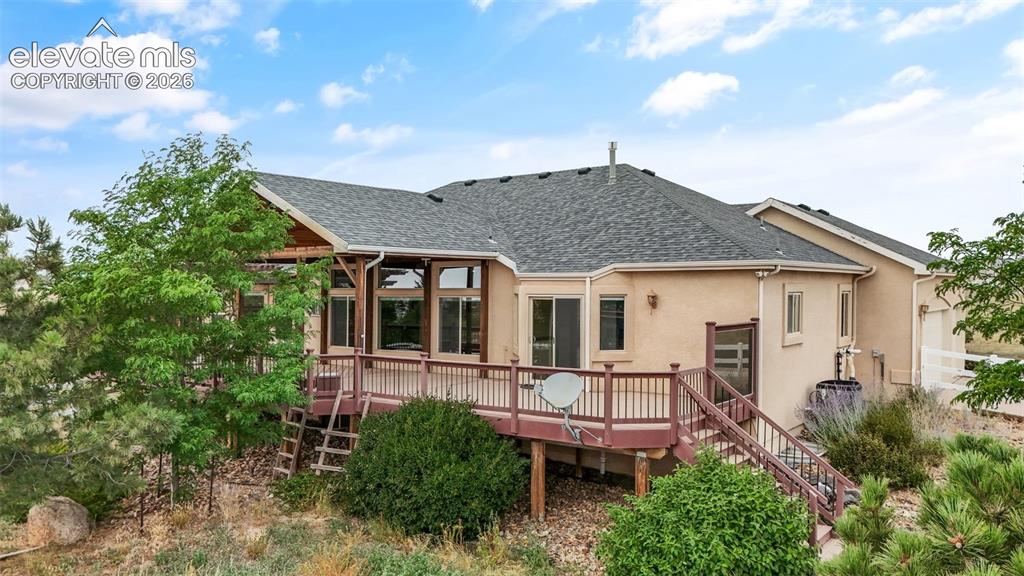 Image 43 of 49: Expansive rear deck with wood railing, outdoor staircase, and an attached c