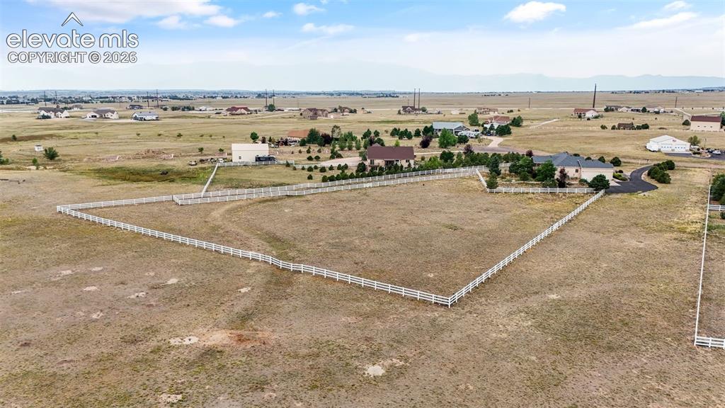 Image 44 of 49: Expansive land parcel featuring white fence boundaries, paved driveways, an