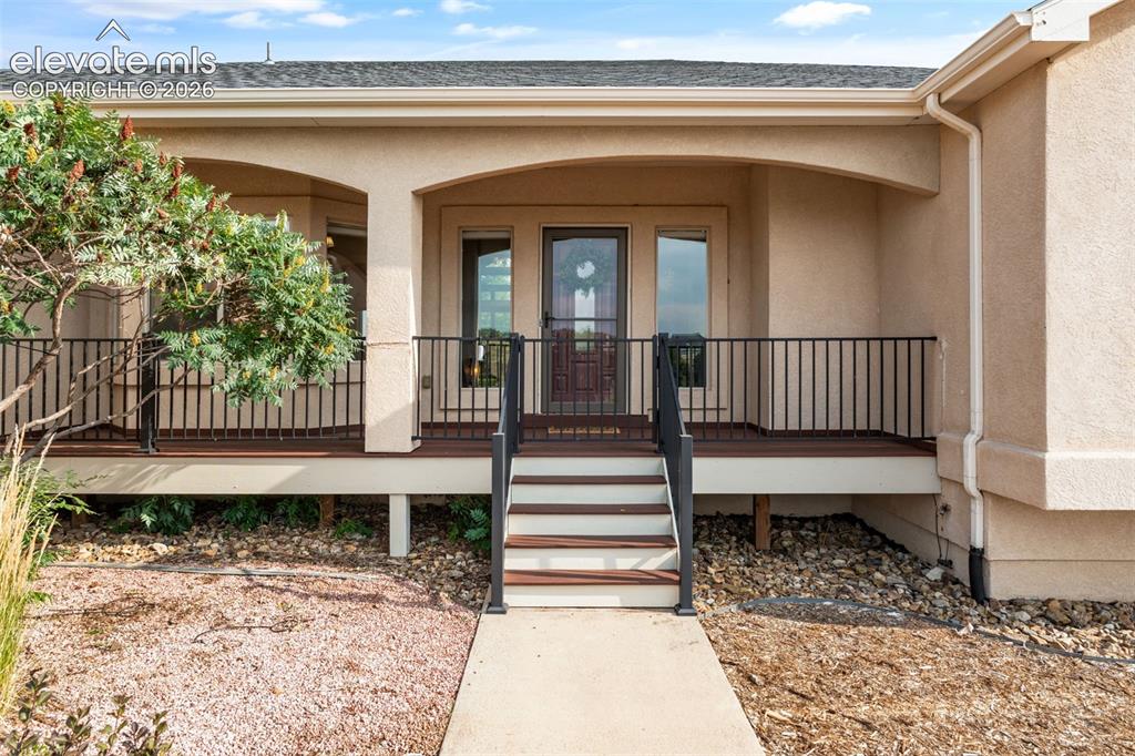 Image 5 of 49: Entry porch featuring arched stucco detailing, black metal railings, compos