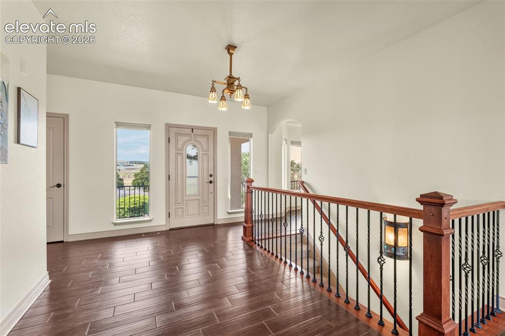 Image 7 of 49: Entryway featuring dark wood-finish flooring, a decorative front door, and