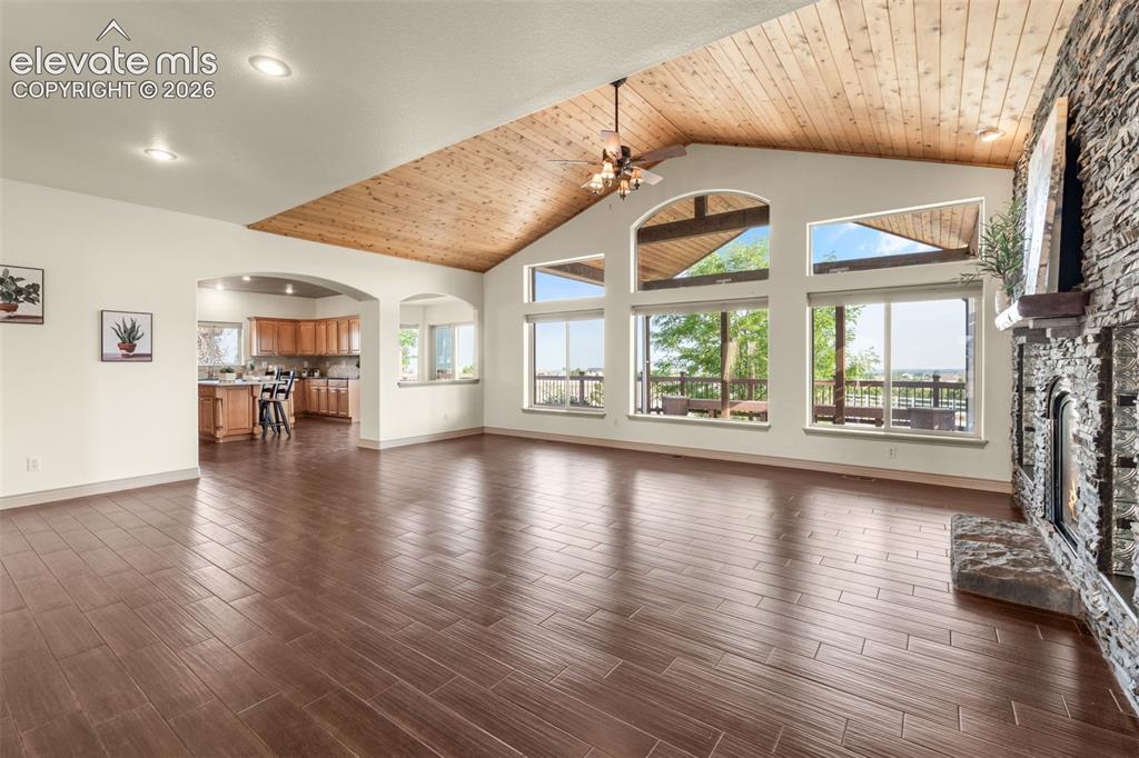 Image 9 of 49: Vaulted wood-finish ceiling, expansive windows, floor-to-ceiling stone fire