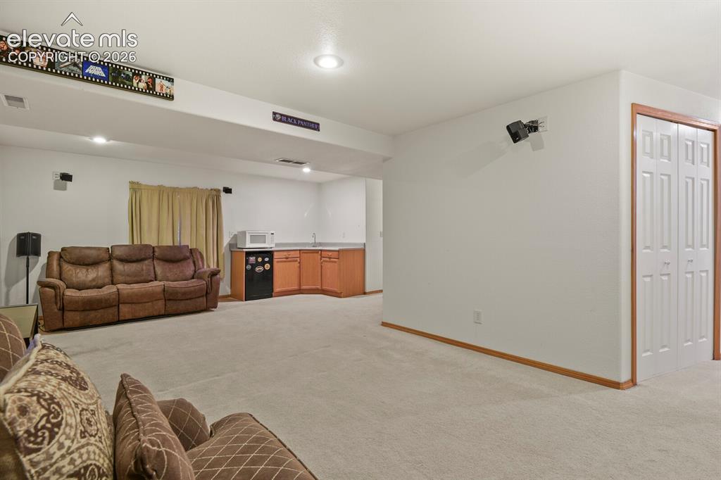 Image 32 of 44: Downstairs Family Room with wet bar in the corner.