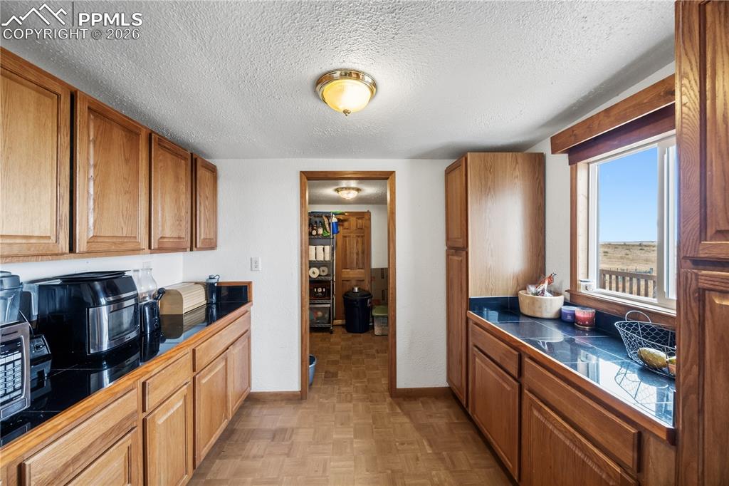 Image 11 of 47: Kitchen featuring a textured ceiling, wood finish cabinets, parquet floorin