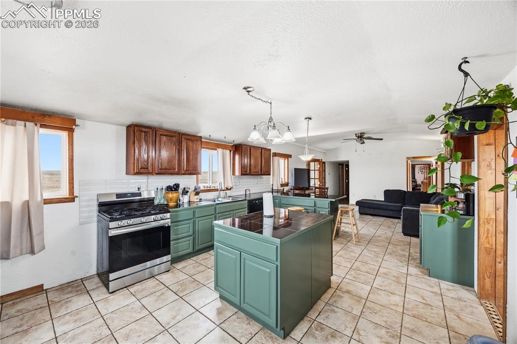 Image 18 of 47: Kitchen featuring a center island, dark countertops, gas stove, a peninsula
