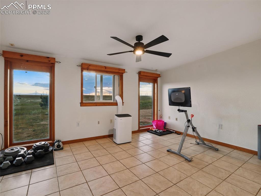 Image 20 of 47: Exercise area with a ceiling fan and light tile patterned flooring