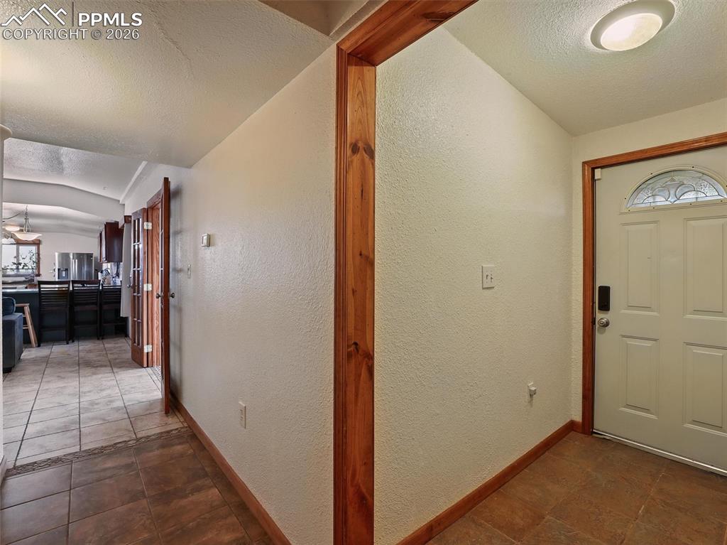 Image 21 of 47: Foyer featuring a textured wall and dark stone finish flooring