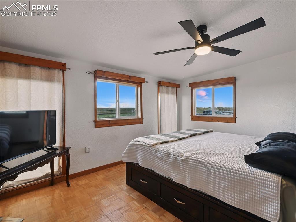 Image 23 of 47: Bedroom with parquet floors, a textured ceiling, a ceiling fan, and a textu