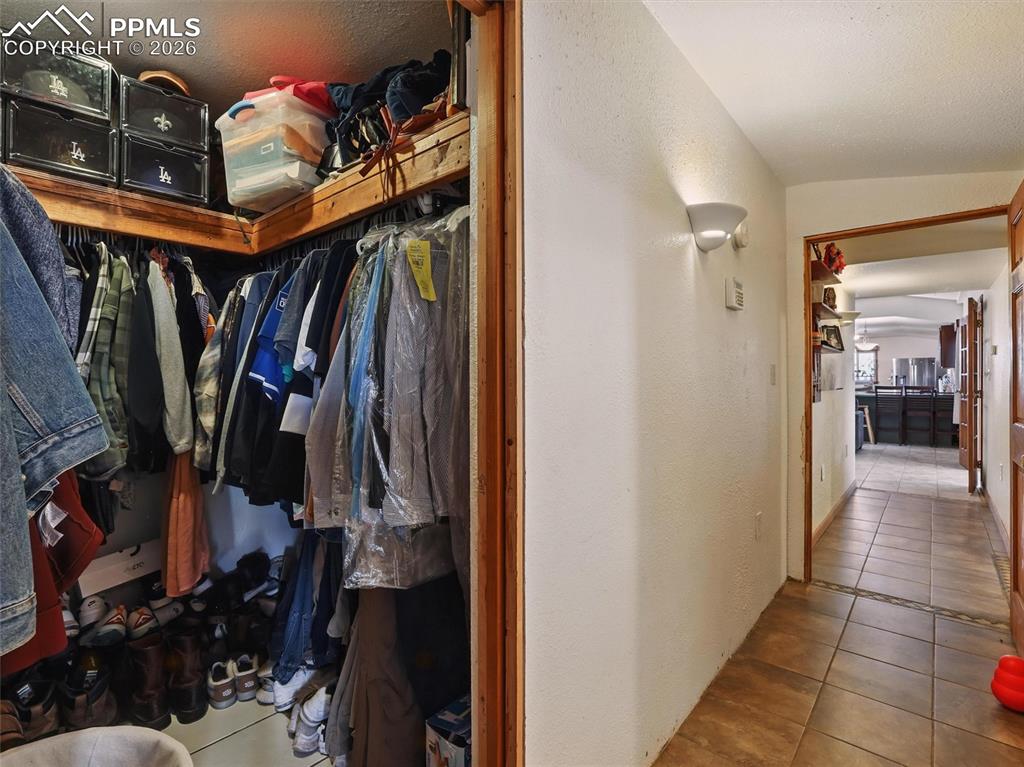 Image 25 of 47: Walk in closet featuring light tile patterned floors and vaulted ceiling
