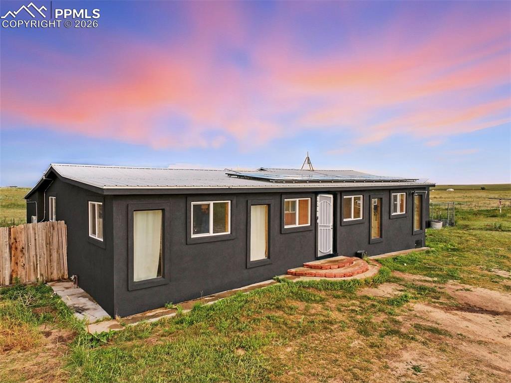 Image 3 of 47: Rear view of house featuring solar panels and a metal roof