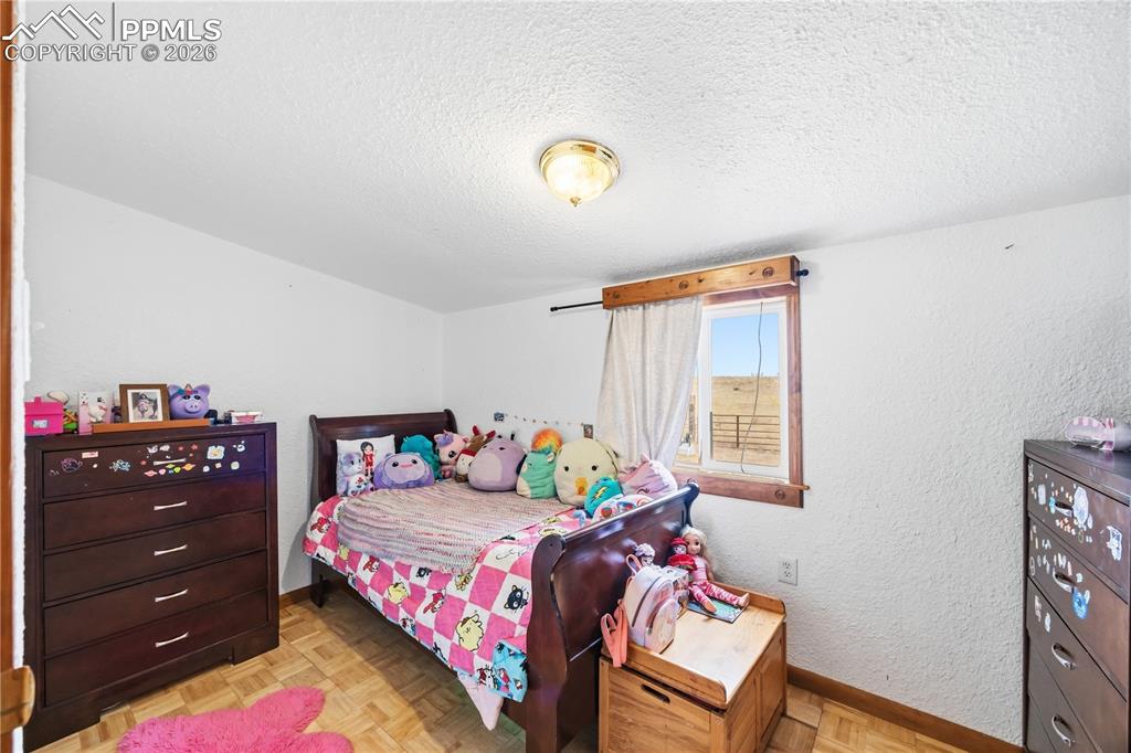 Image 35 of 47: Bedroom featuring parquet flooring, a textured ceiling, and a textured wall