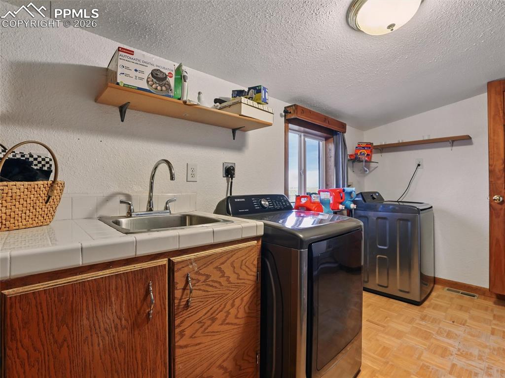 Image 37 of 47: Laundry room featuring parquet flooring, cabinet space, washing machine and
