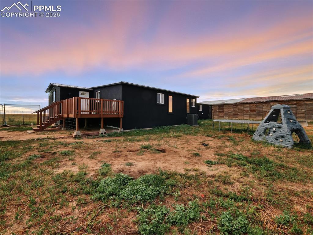 Image 41 of 47: Back of property at dusk with a deck and a trampoline