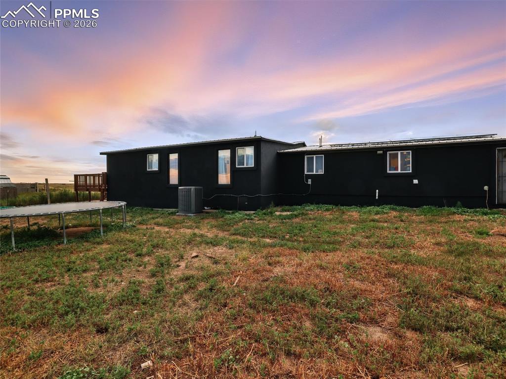 Image 42 of 47: Back of property at dusk featuring a trampoline and a lawn
