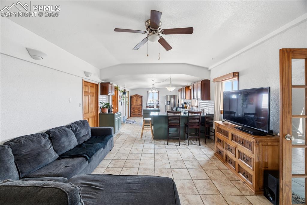 Image 6 of 47: Living room featuring ceiling fan, vaulted ceiling, light tile patterned fl