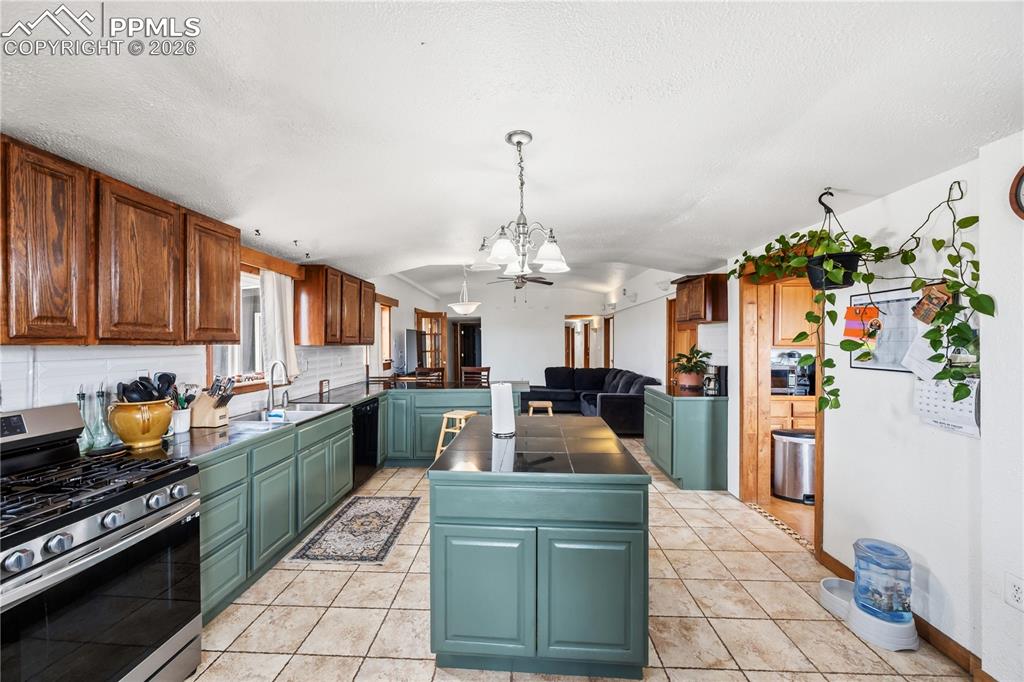 Image 9 of 47: Kitchen featuring stainless steel range with gas stovetop, dark countertops