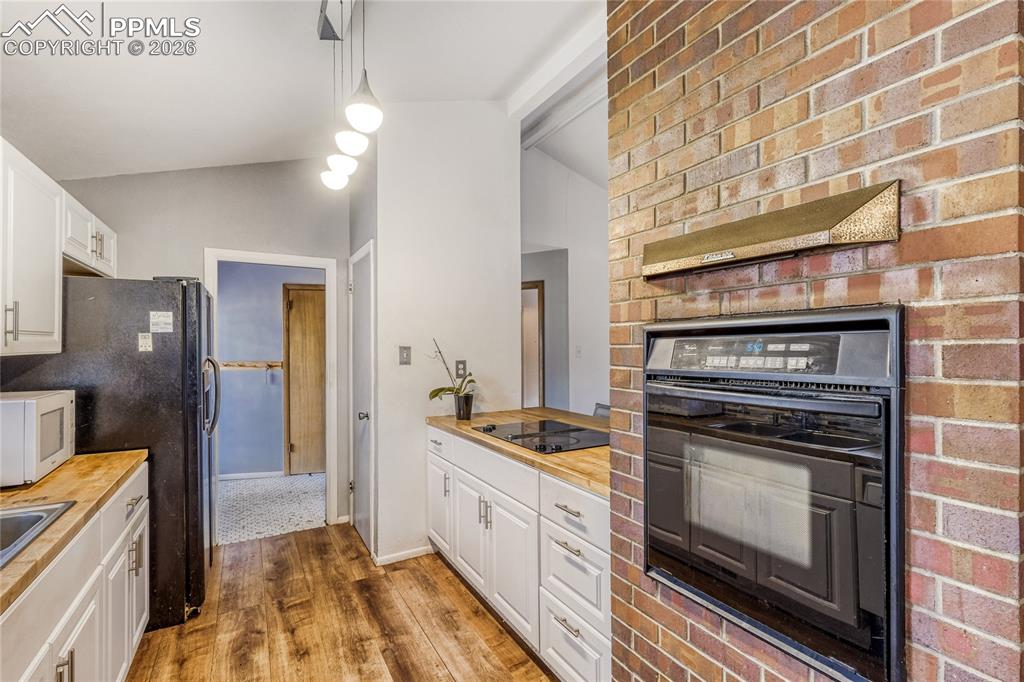 Image 17 of 29: Living area featuring a stone-clad fireplace and wood-finish flooring