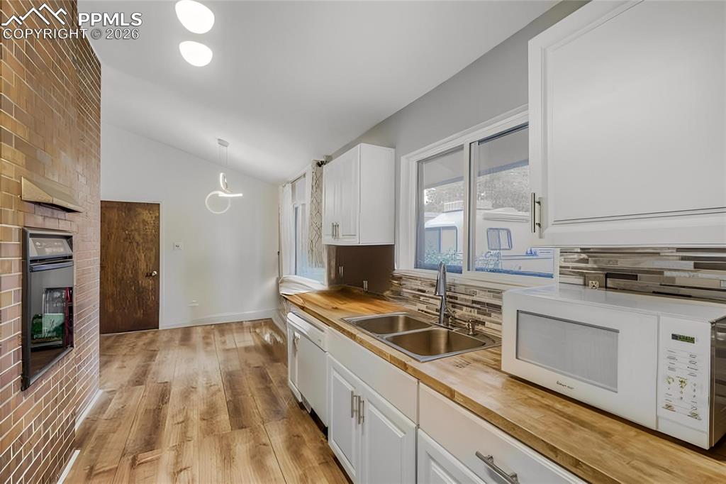 Image 8 of 29: Spacious living area featuring a vaulted ceiling with exposed beams, wood-f