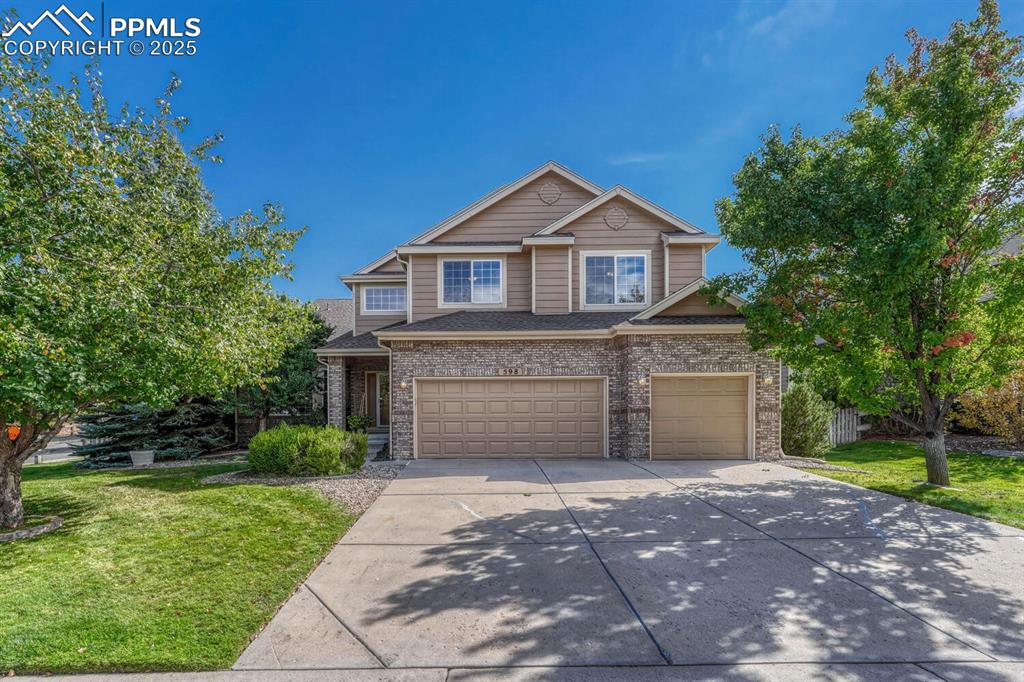 Caption: View of front of home with concrete driveway, a front yard, a garage, and brick siding