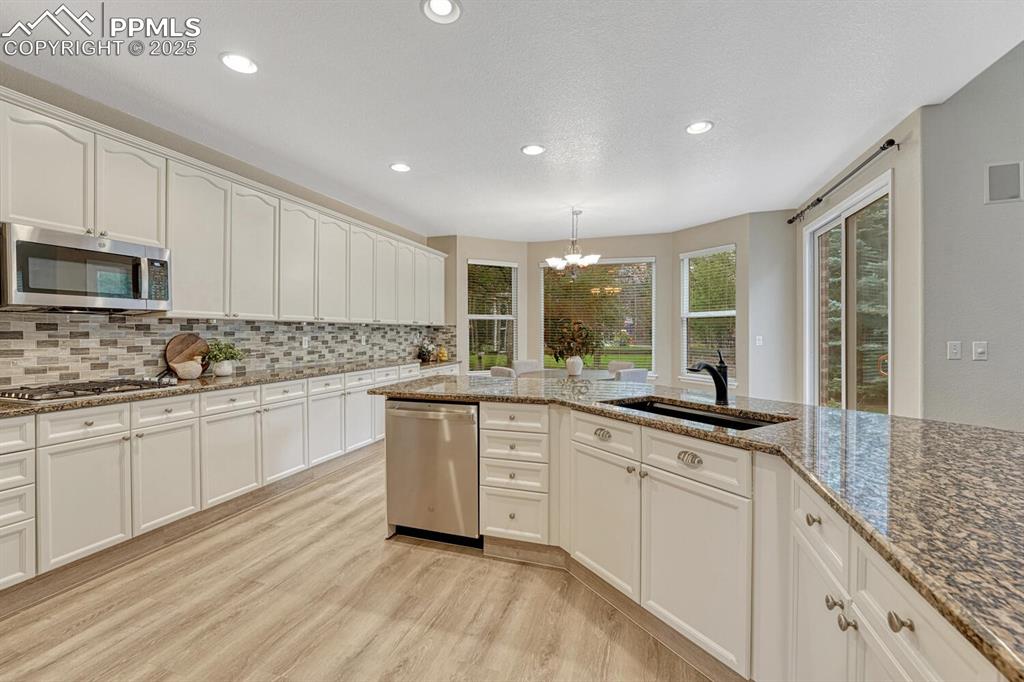 Image 10 of 50: Kitchen featuring a chandelier, stainless steel appliances, tasteful backsp
