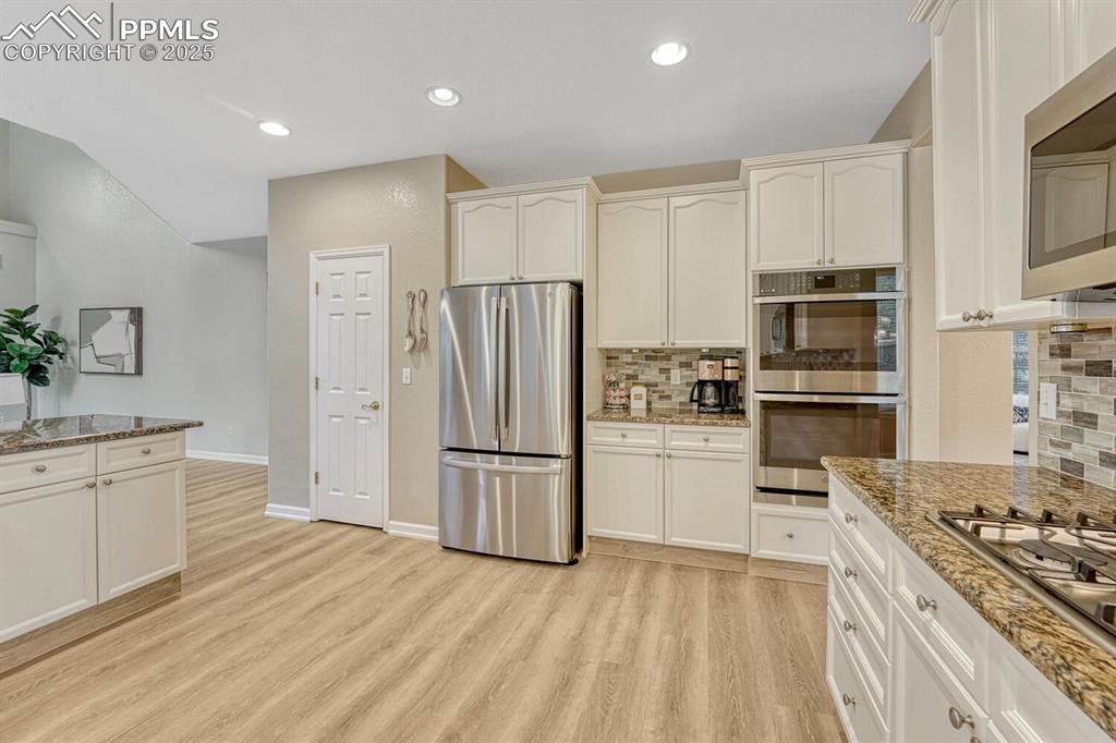Image 12 of 50: Kitchen with appliances with stainless steel finishes, light wood-style flo