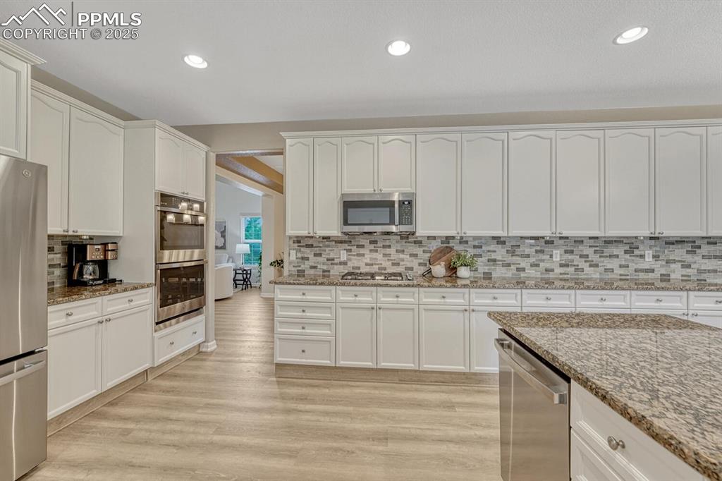 Image 13 of 50: Kitchen with stainless steel appliances, decorative backsplash, white cabin