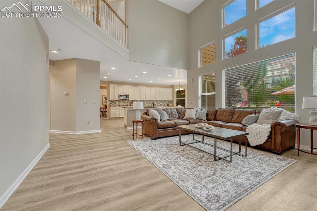 Image 17 of 50: Living room featuring a towering ceiling, light wood-style floors, and rece