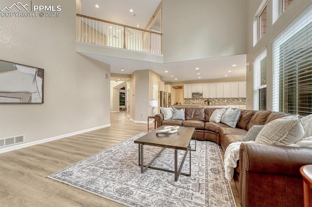 Image 18 of 50: Living room featuring a high ceiling, light wood-type flooring, and recesse