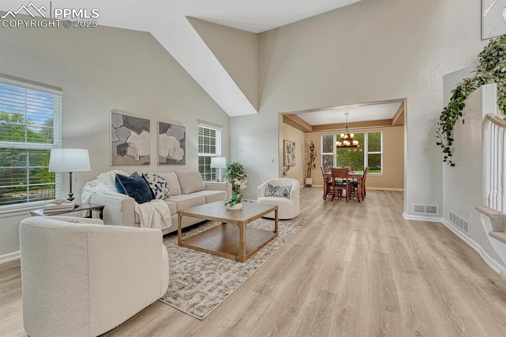 Image 2 of 50: Living room featuring light wood-type flooring, a chandelier, and high vaul
