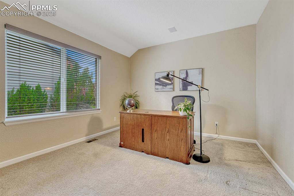 Image 20 of 50: Carpeted office space with baseboards and lofted ceiling