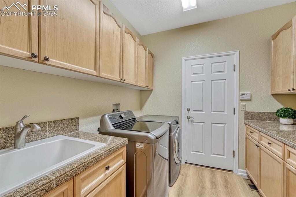 Image 21 of 50: Laundry room featuring independent washer and dryer, cabinet space, light w