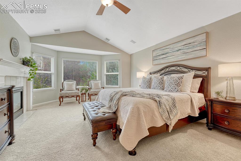 Image 26 of 50: Bedroom featuring light colored carpet, lofted ceiling, ceiling fan, and a