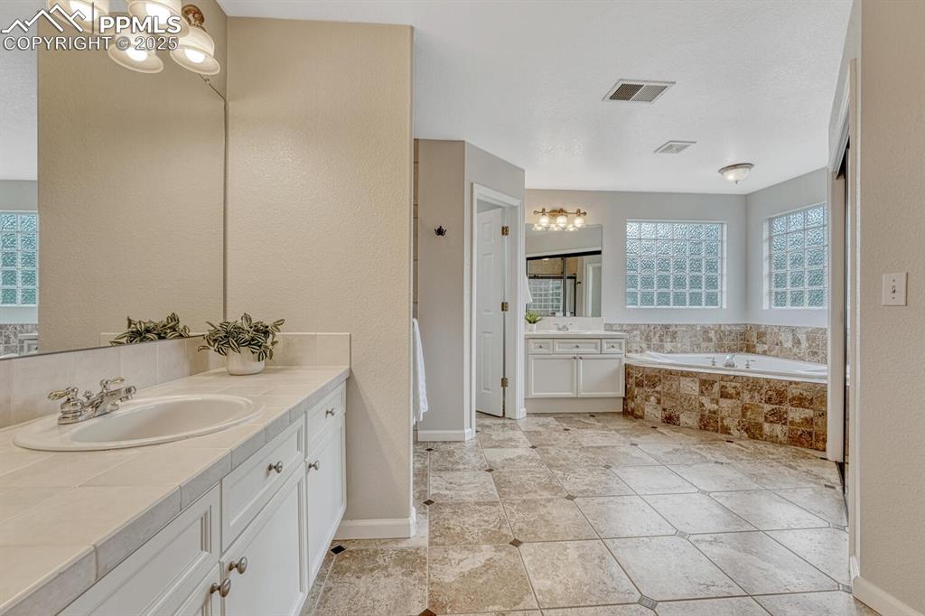 Image 27 of 50: Full bathroom featuring two vanities and a garden tub