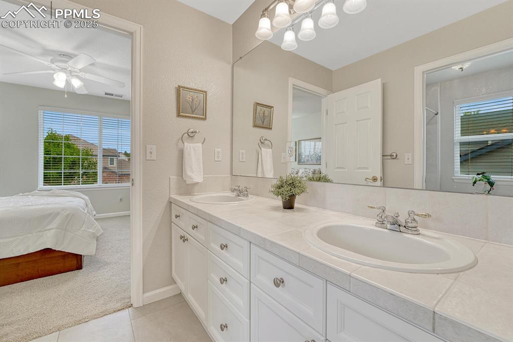 Image 29 of 50: Ensuite bathroom featuring double vanity, tile patterned flooring, and ceil