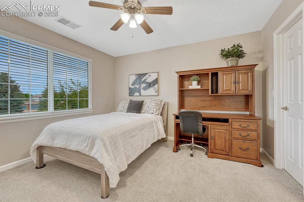 Image 33 of 50: Bedroom featuring light colored carpet, a desk, and a ceiling fan