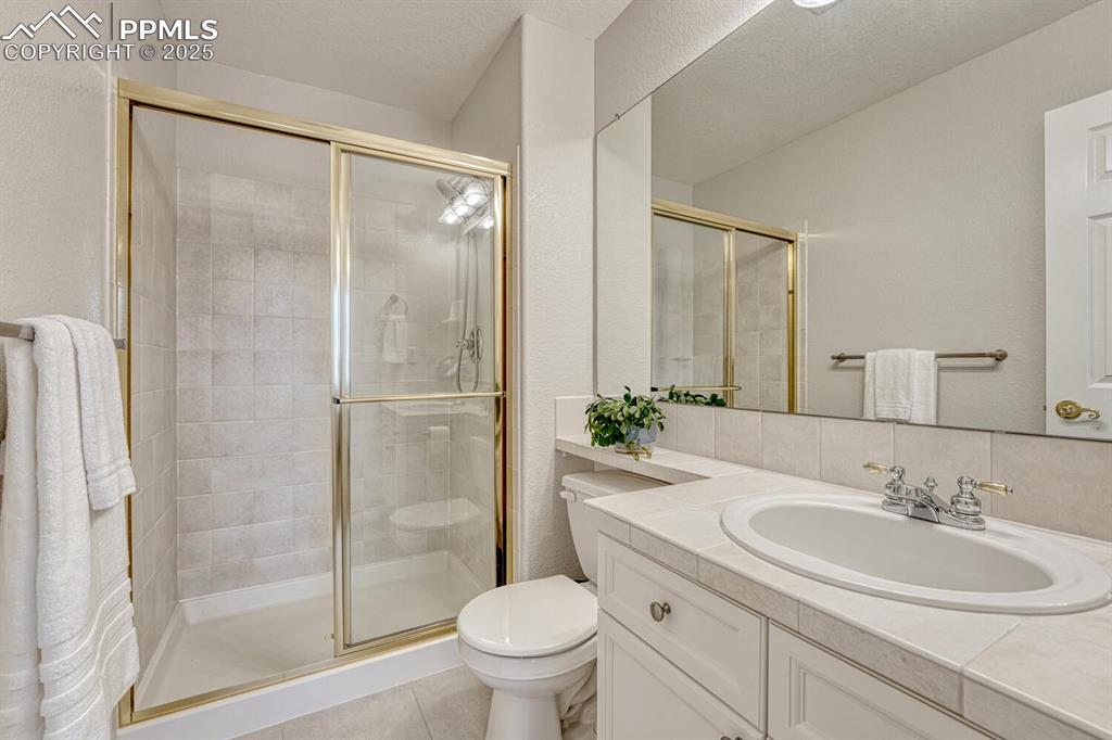 Image 35 of 50: Bathroom with a shower stall, vanity, tile patterned flooring, and decorati