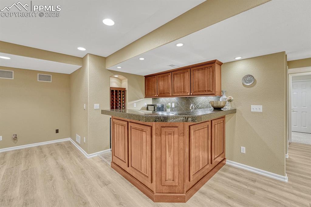 Image 38 of 50: Kitchen featuring light wood finished floors, tasteful backsplash, brown ca