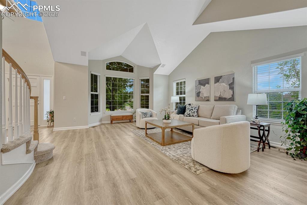 Image 4 of 50: Living room featuring stairs, high vaulted ceiling, and light wood-style fl