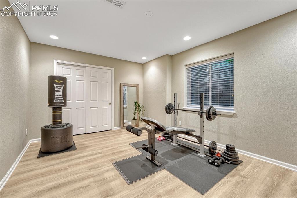 Image 41 of 50: Workout area with wood finished floors, a textured wall, and recessed light