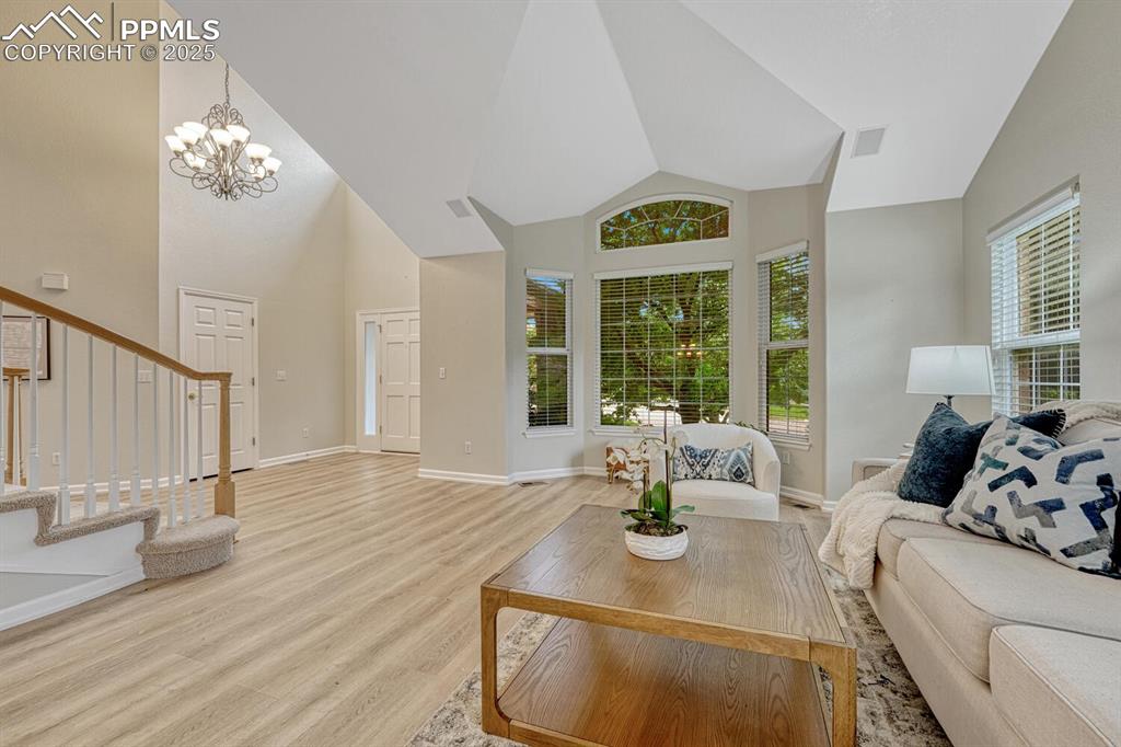 Image 5 of 50: Living room featuring stairway, light wood-style flooring, a chandelier, an