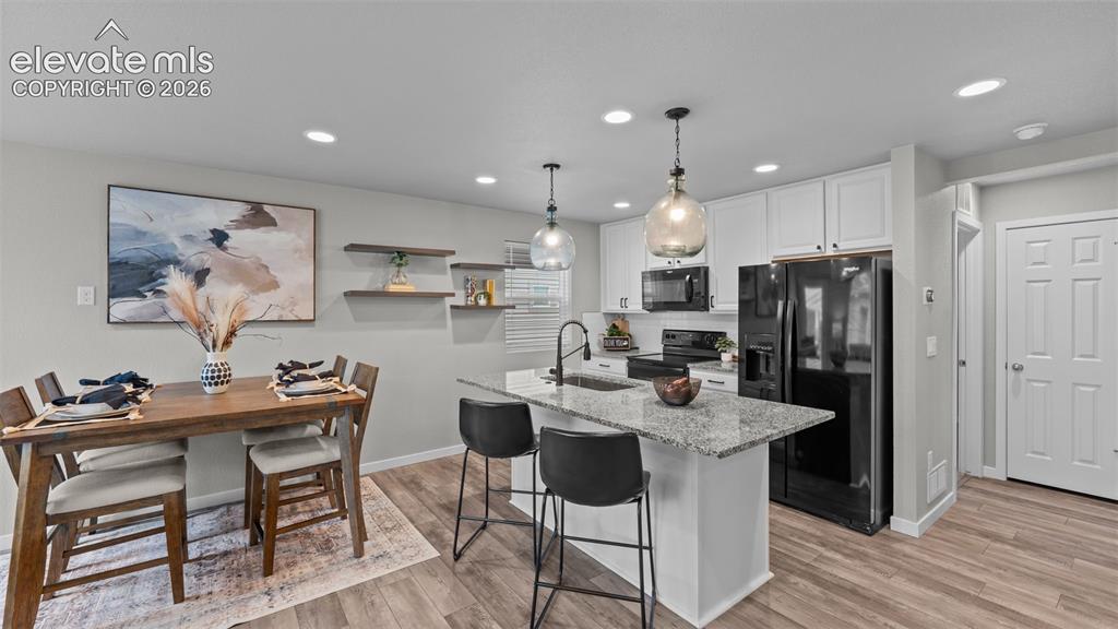 Image 10 of 34: Kitchen featuring white cabinetry, stone-surface island with an integrated 