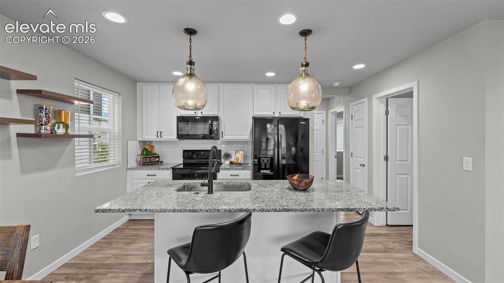 Image 11 of 34: Kitchen featuring white shaker-style cabinetry, stone-finish countertops, c