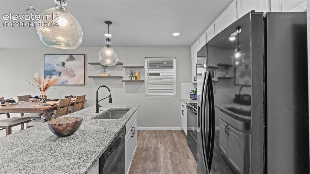 Image 12 of 34: Kitchen featuring white cabinetry, stone-finish countertops, wood-finish fl