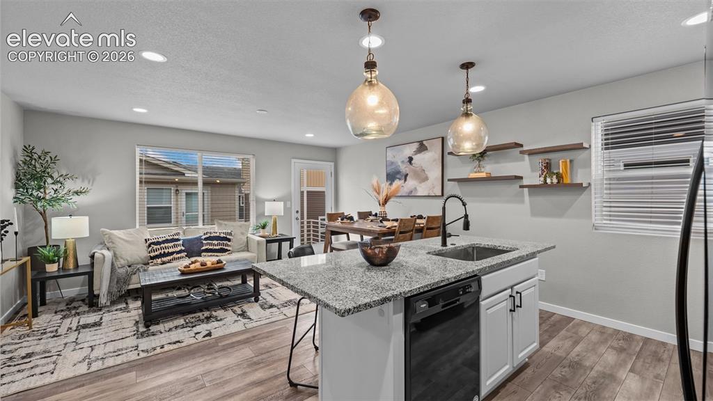 Image 13 of 34: Kitchen featuring a stone-surface island, white cabinetry, matte black hard