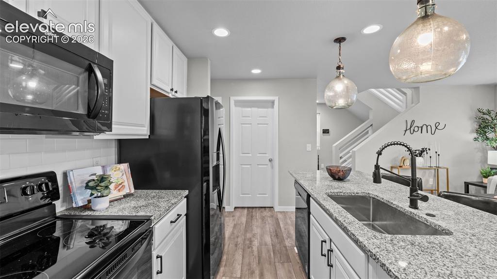 Image 15 of 34: Kitchen featuring white shaker-style cabinetry, stone-finish countertops, s