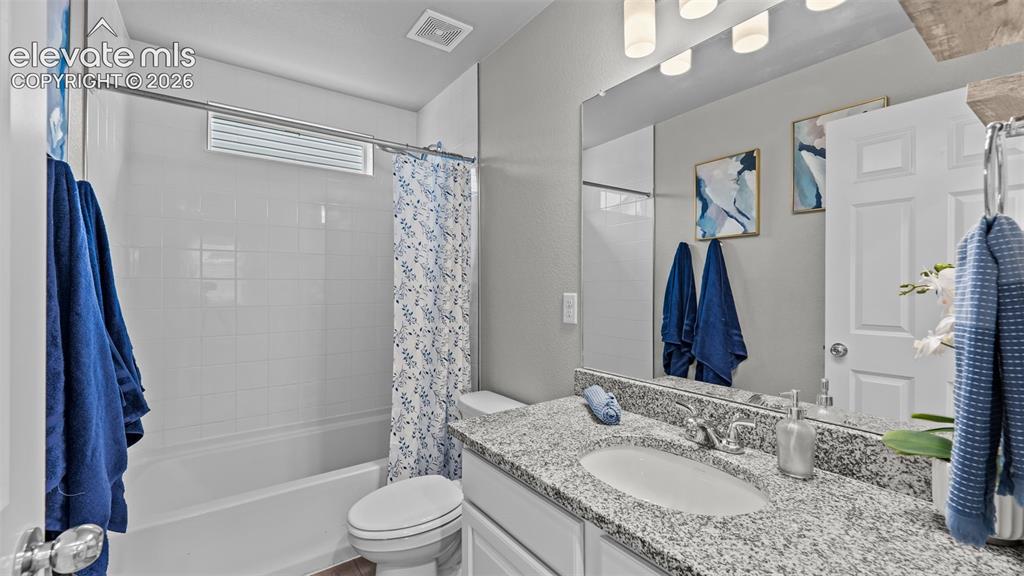 Image 16 of 34: Bathroom featuring a stone-surface vanity with an integrated basin, a large