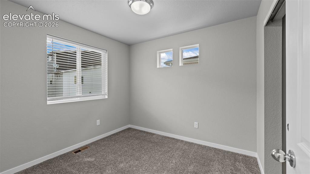 Image 18 of 34: Neutral-toned interior room featuring wall-to-wall carpeting, a multi-pane