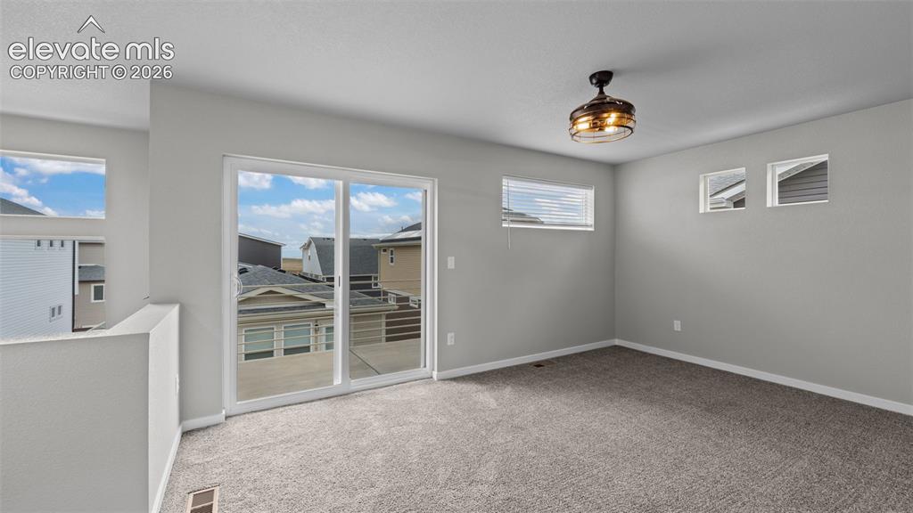 Image 22 of 34: Neutral-toned interior space featuring wall-to-wall carpeting, sliding glas