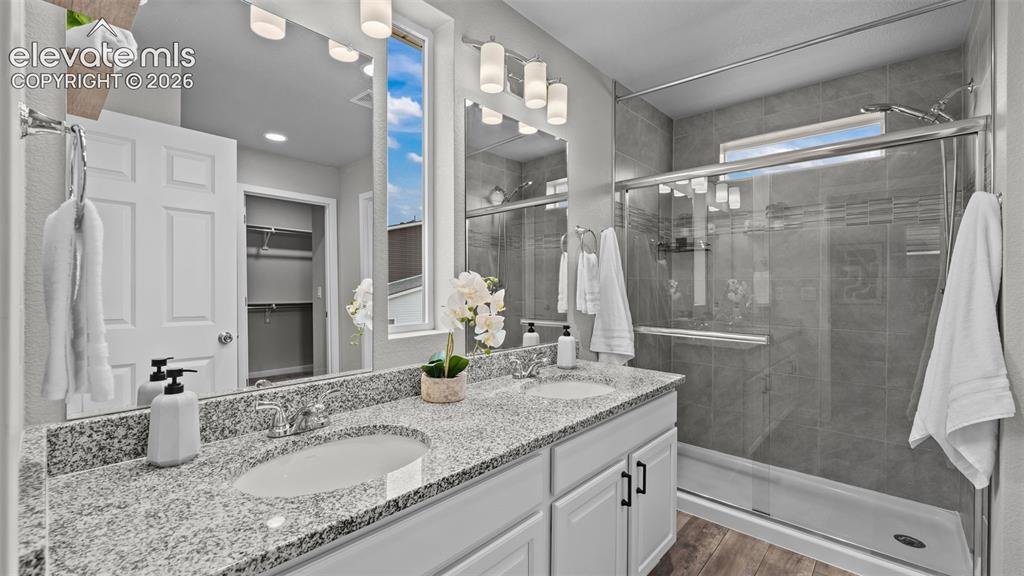 Image 27 of 34: Dual-sink vanity with stone-style countertops, shaker-style cabinetry, glas