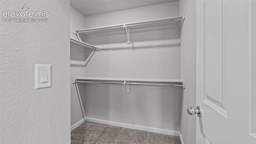 Image 30 of 34: Storage area featuring dual-level shelving and integrated hanging rods, fin