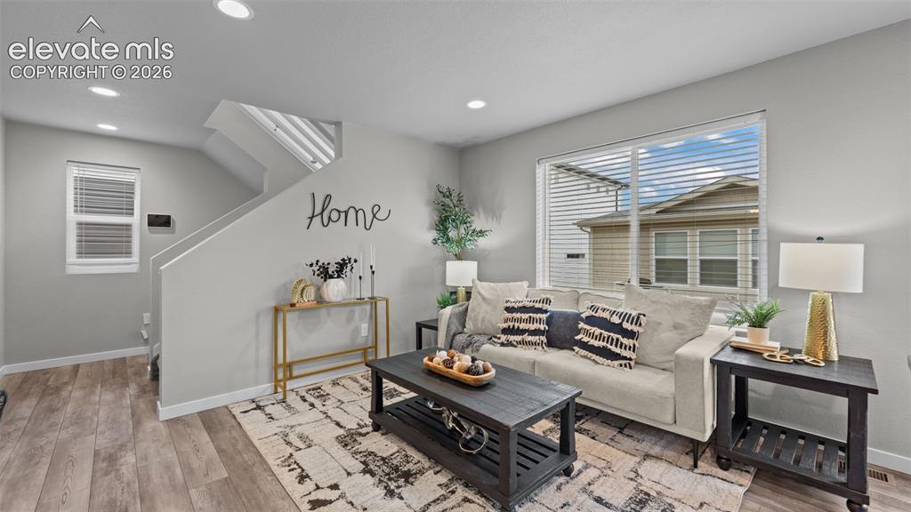Image 7 of 34: Living area featuring wood-finish flooring, recessed lighting, and a large